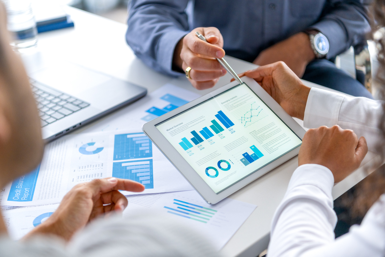 Close up of three people looking at financial data with graphs and charts. Our Wealth Approach